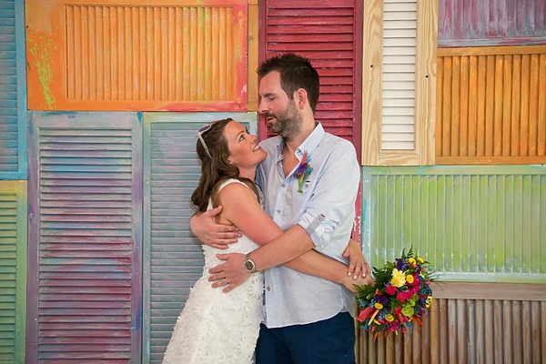 Bride and groom embrace before colorful window shades SB Barbados free