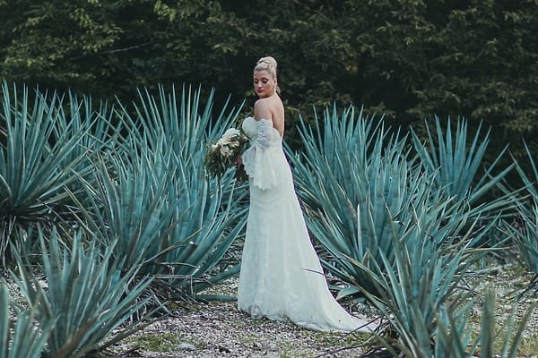 A bride in white holds her bouquet among agaves during a destination wedding at Hotel Xcaret.