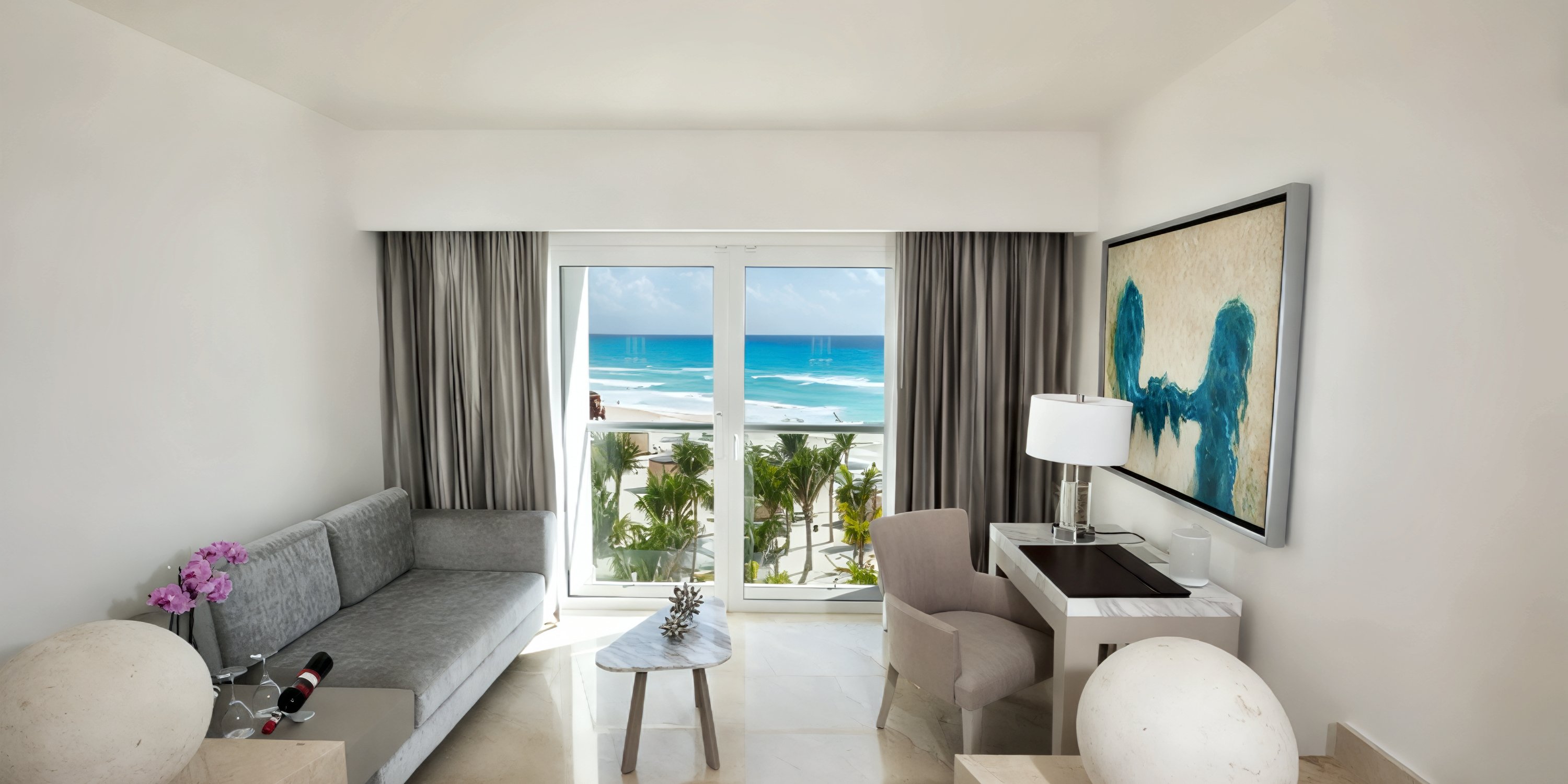 Elegant modern room at Le Blanc Spa Resort, perfect for a destination wedding, featuring breathtaking views of the ocean, palm trees, and beach through expansive windows.