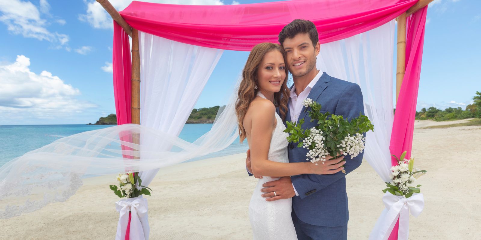 A bride and groom posing under a pink wedding arch on the beach during their Royalton Antigua wedding.