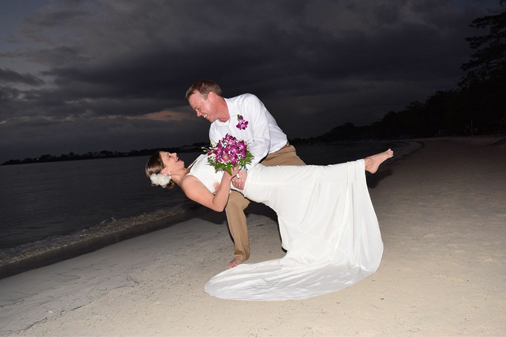 Groom dips his bride on the beach at a destination wedding