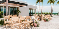 Wooden chairs and florals set up for a destination wedding on the sunny patio at Secrets Moxche Playa del Carmen.