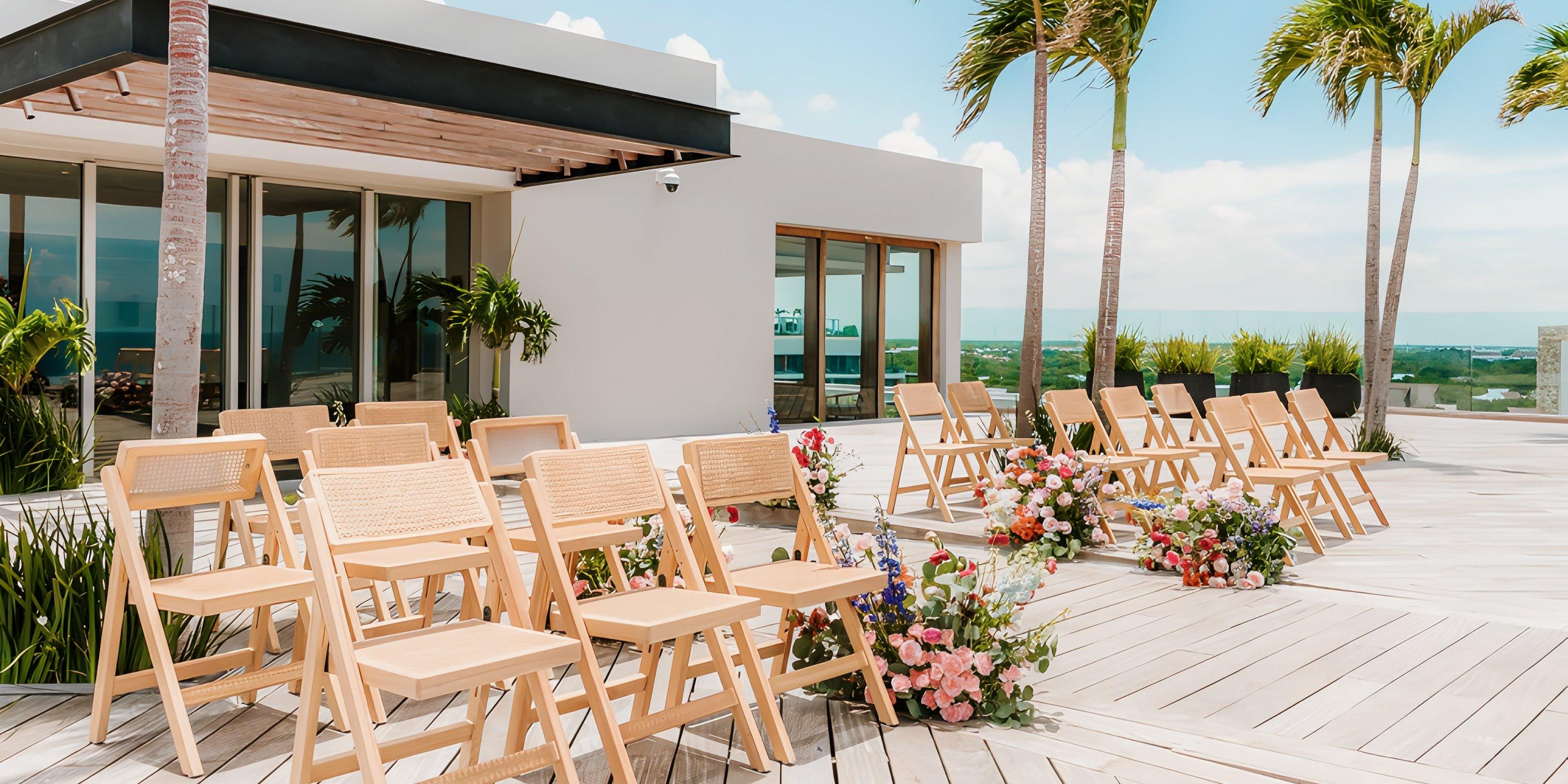 Wooden chairs and florals set up for a destination wedding on the sunny patio at Secrets Moxche Playa del Carmen.