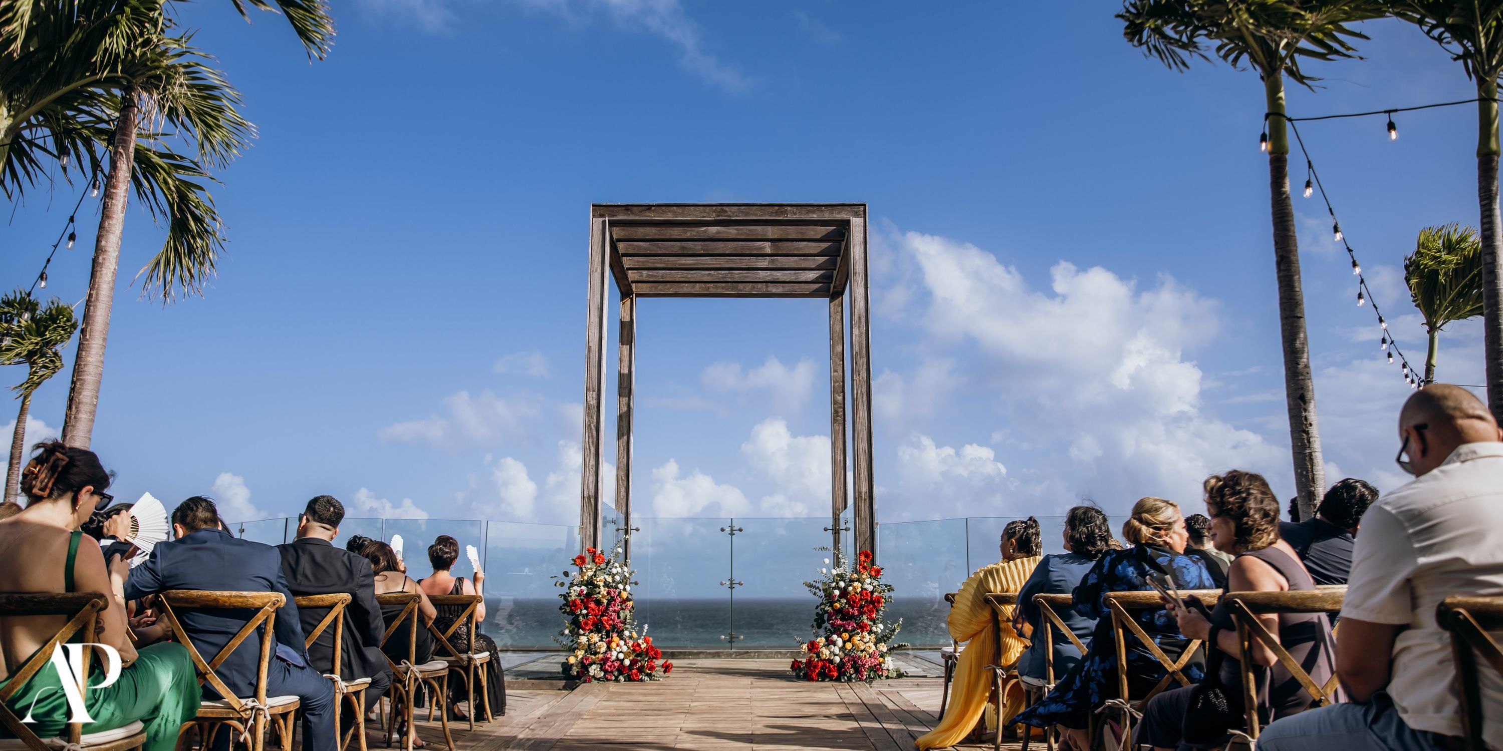 Destination wedding at Secrets Moxche Playa del Carmen: wooden arch, florals, and guests seated outdoors.
