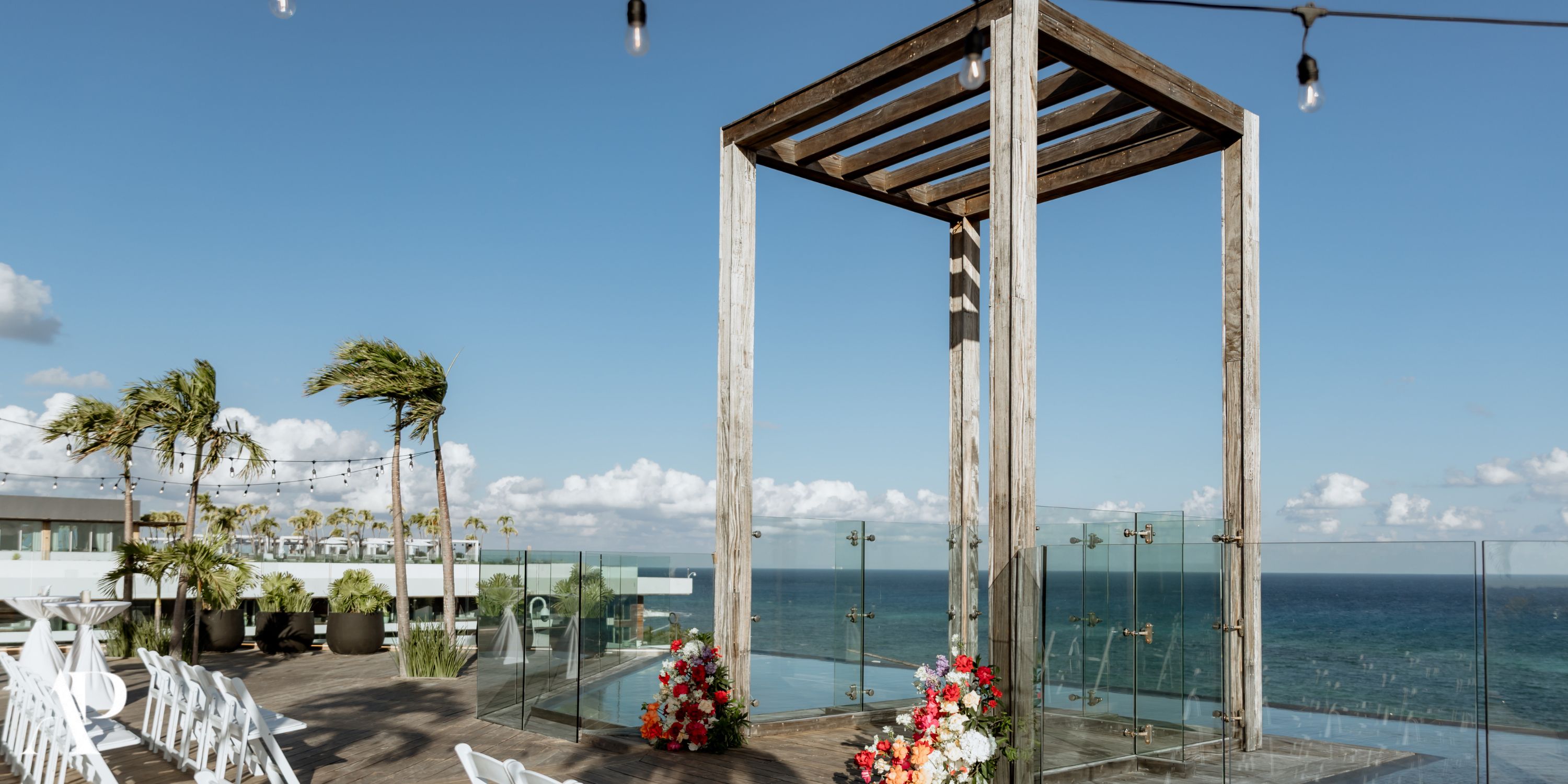 Destination wedding at Secrets Moxche Playa del Carmen: floral wooden altar, ocean backdrop, clear skies.