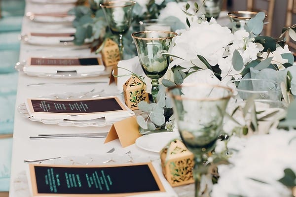 Chic destination wedding table at Accra Beach Hotel & Spa with green glasses and gold-trimmed d&eacute;cor.
