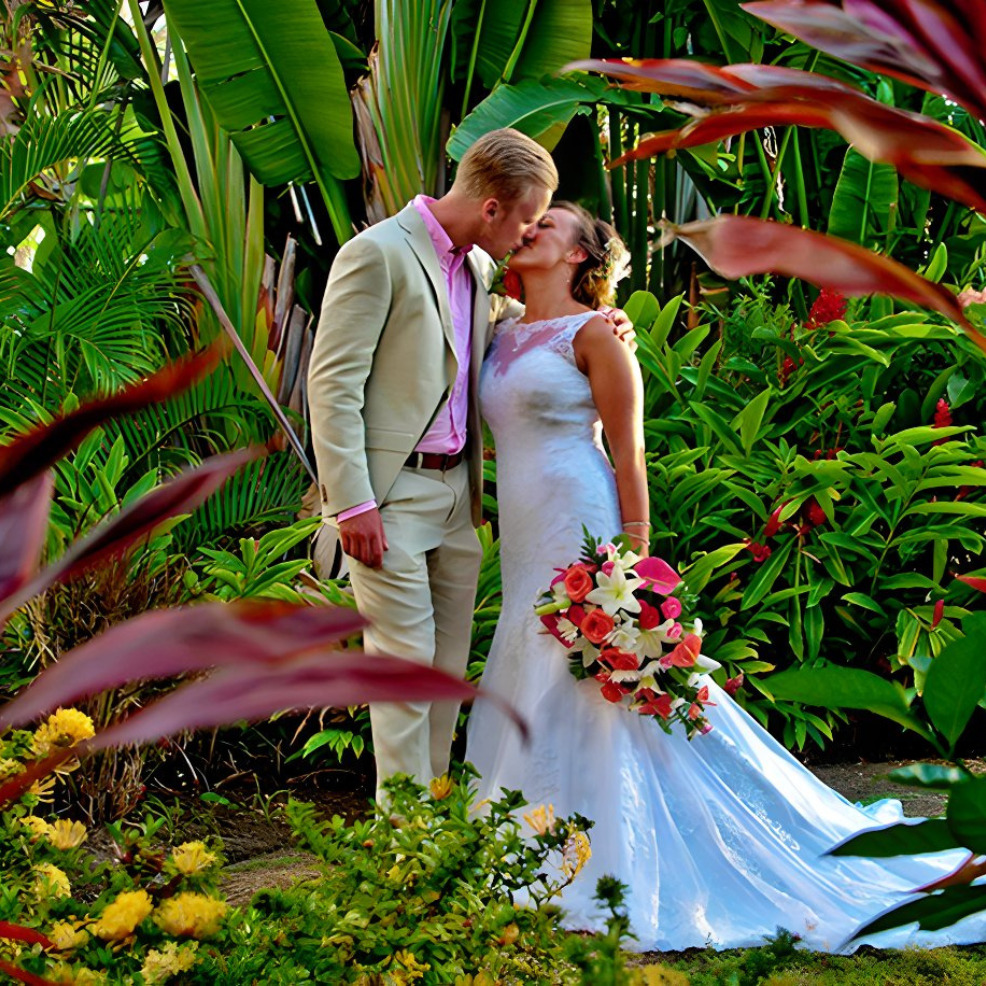 A bride and groom kissing in a tropical garden during their destination wedding.