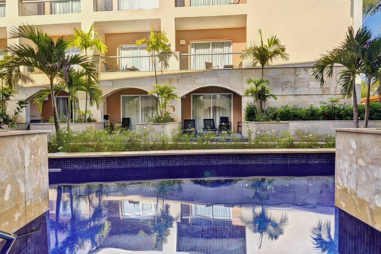 Pool in the foreground and Hideaway at Royalton Punta Cana's facade in the background an affordable Dominican Republic wedding package