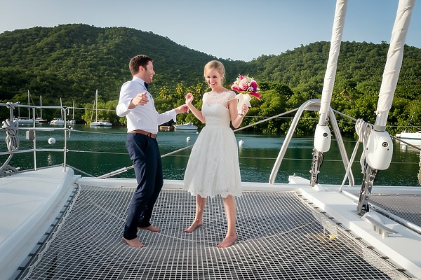 A couple in wedding attire poses on a catamaran, celebrating their destination wedding in St. Lucia.