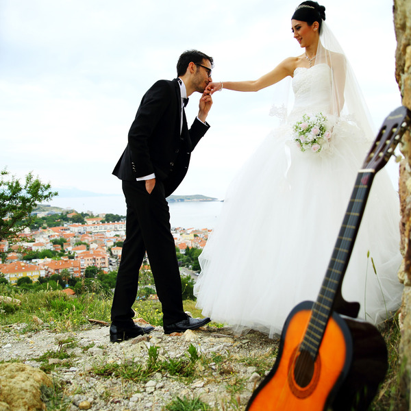 Guitar in the foreground of a man kissing his wife's hand music for your destination wedding