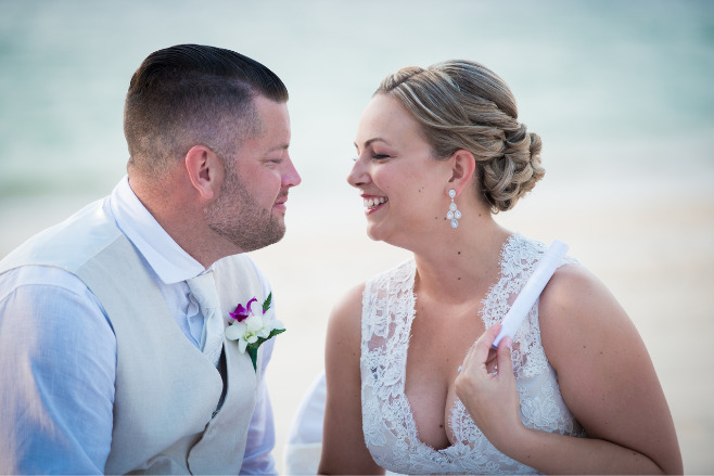 Couple smiling at each other on the beach of a destination wedding