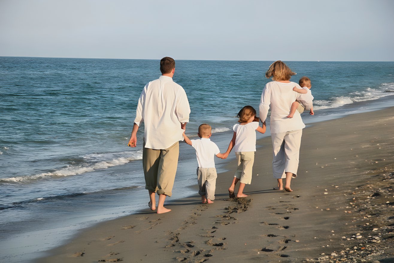 A family walks hand-in-hand on the white sand beaches of a Jamaica family friendly resort