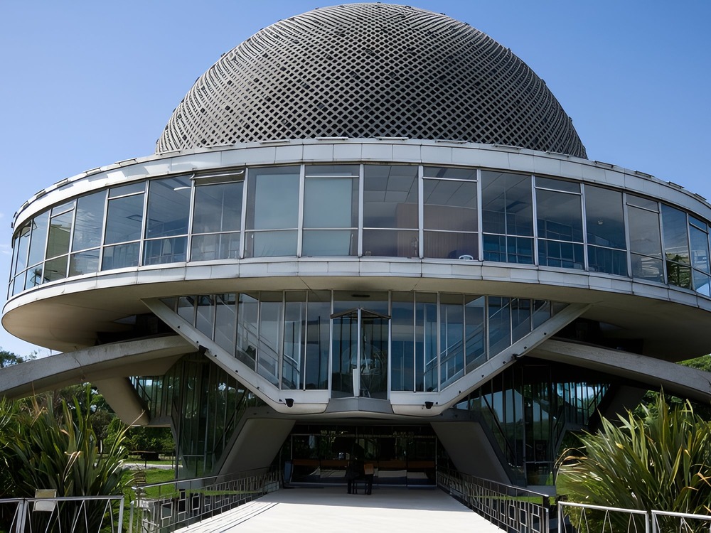 A modern glass building with a domed roof, surrounded by lush greenery—an ideal setting for a unique wedding proposal or an unforgettable destination wedding.