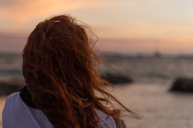 A woman seen from behind with the sunsetting