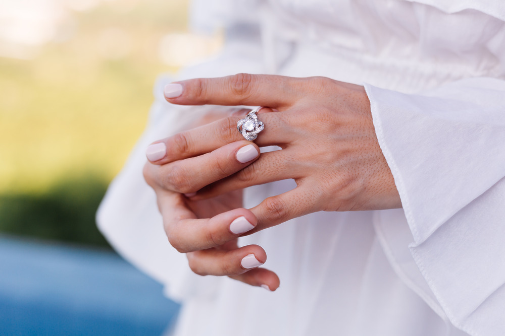Close-up of a person dressed in white, showcasing a large lab-grown diamond ring on their left hand—an elegant choice for a wedding or destination wedding.