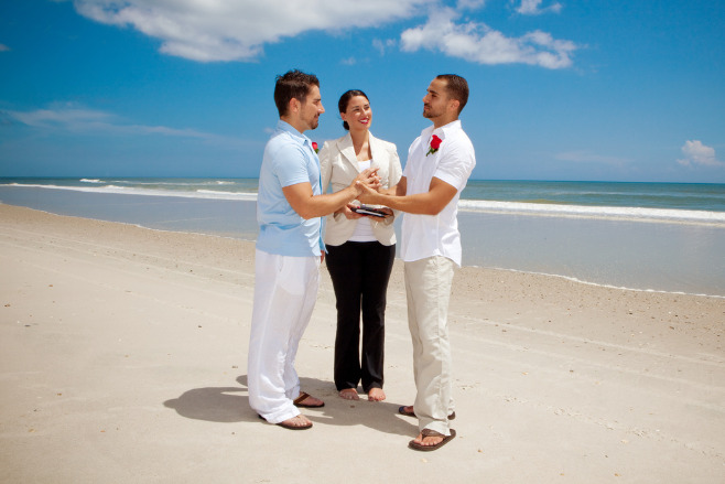 Two men holding hands on a beach for their tropical destination wedding