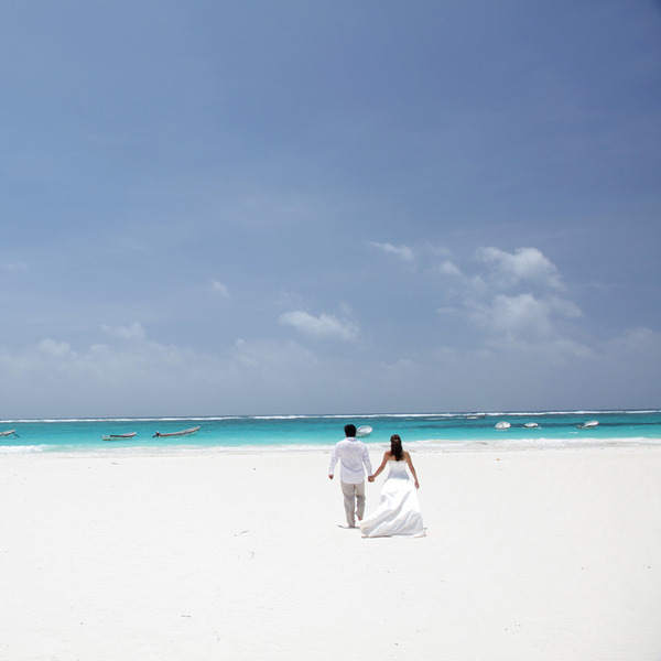 A couple standing hand in hand on a beach after their big day at a Playa destination wedding resort