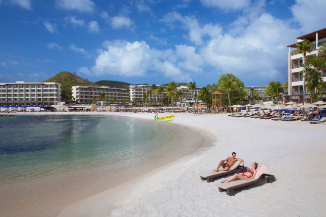 A couple sun lounging at Royalton Antigua, a resort offering destination wedding packages under $5,000
