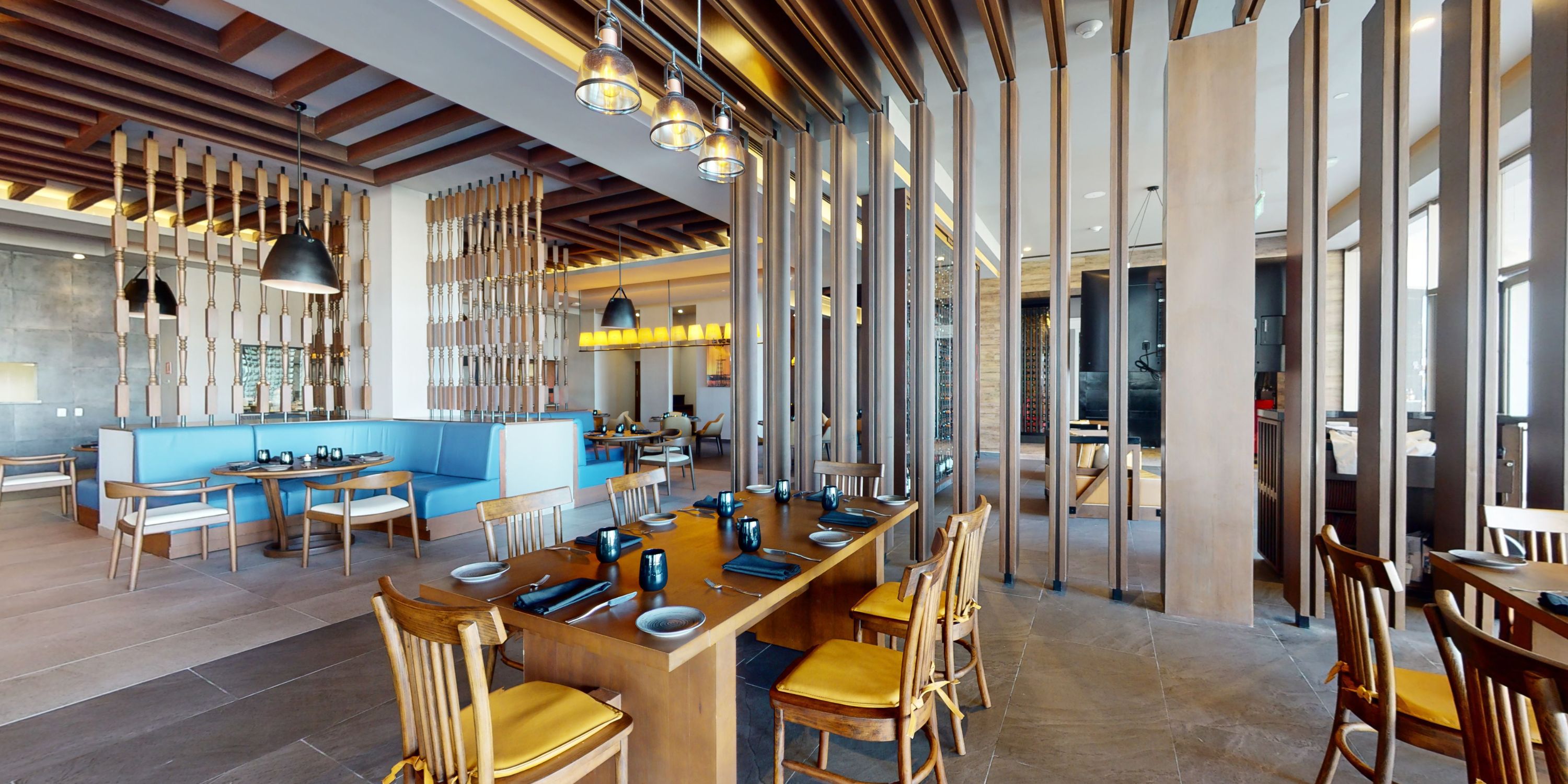 Modern interior for a destination wedding at Royalton Splash Riviera Cancun with wood tables, blue seating, and partitions.