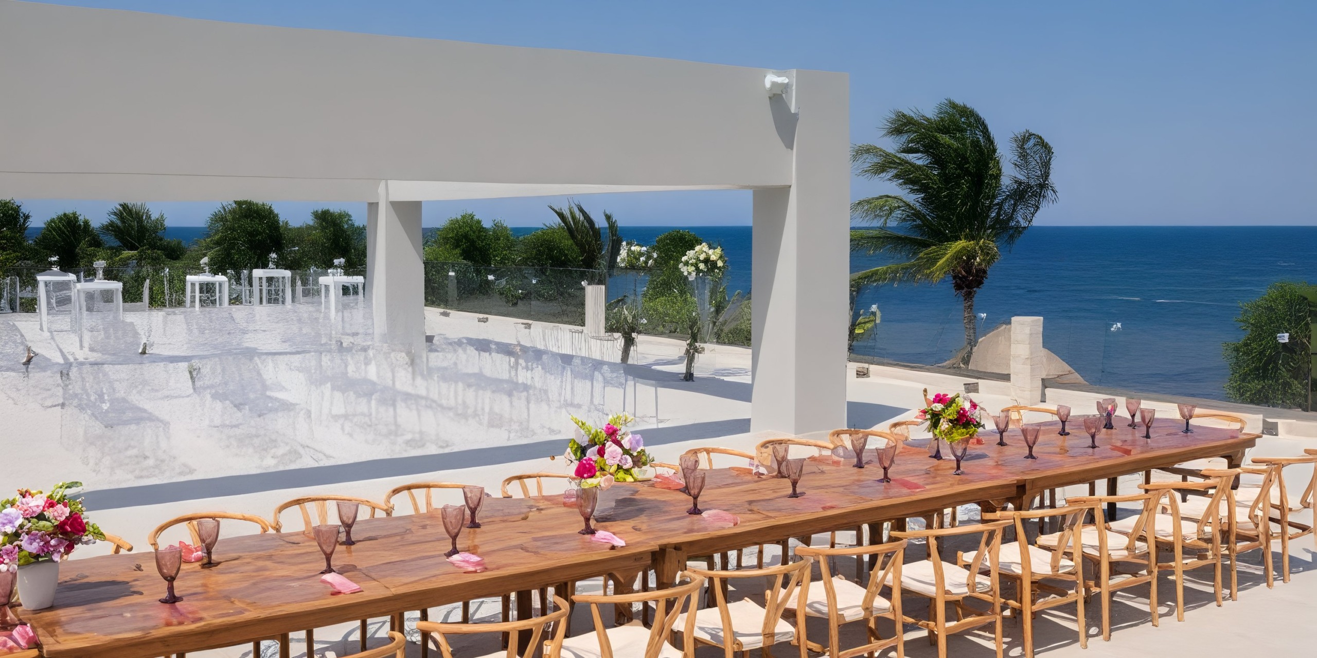 An oceanfront destination wedding at Royalton Splash Riviera Cancun features a beautifully arranged long table adorned with chairs and elegant floral arrangements.