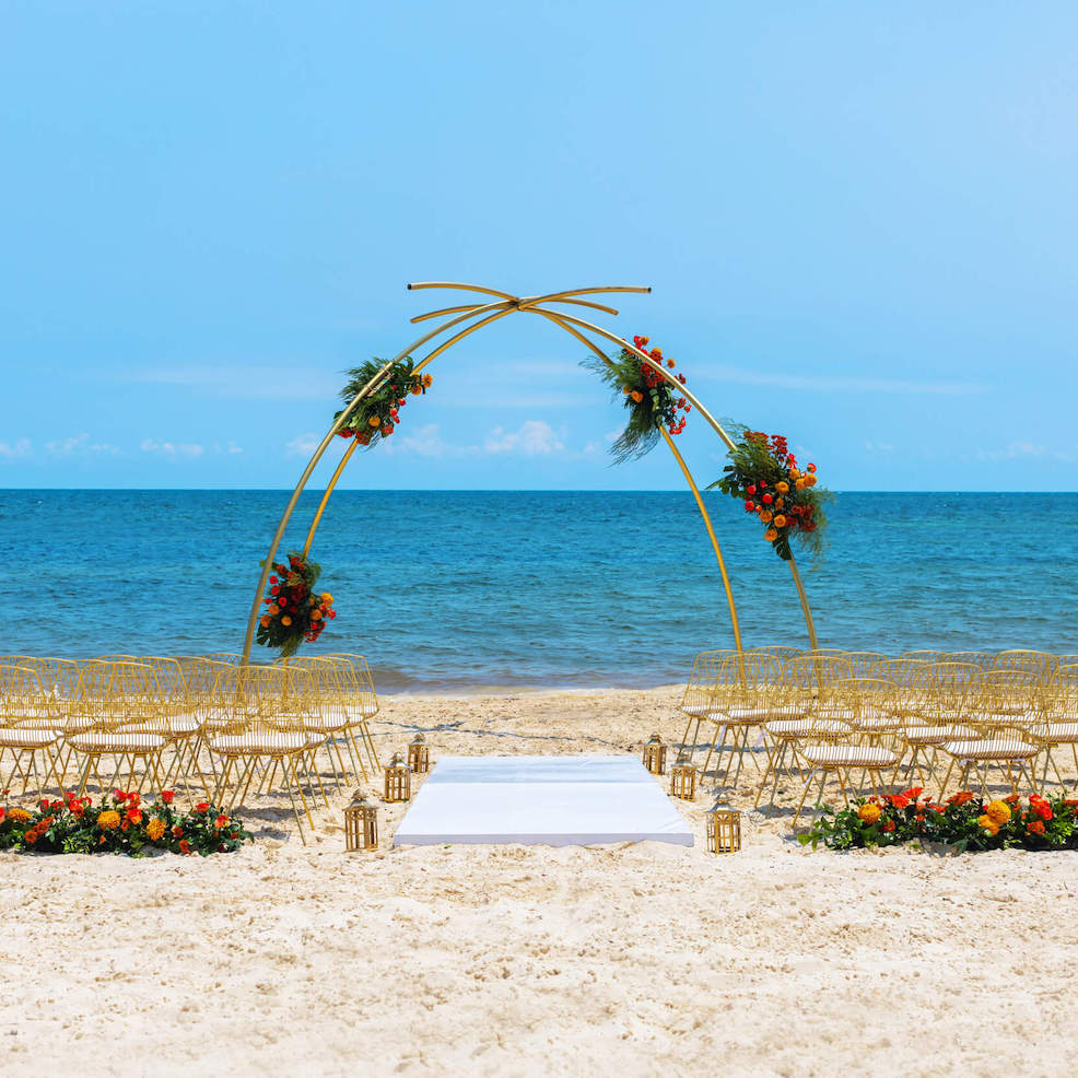 A beautiful destination wedding arrangement featuring an arch and chairs arranged to face the ocean.