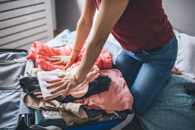 A guest packs their suitcase for a destination wedding invitation