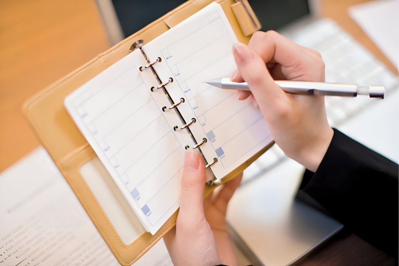 Someone holds up a journal and a pen