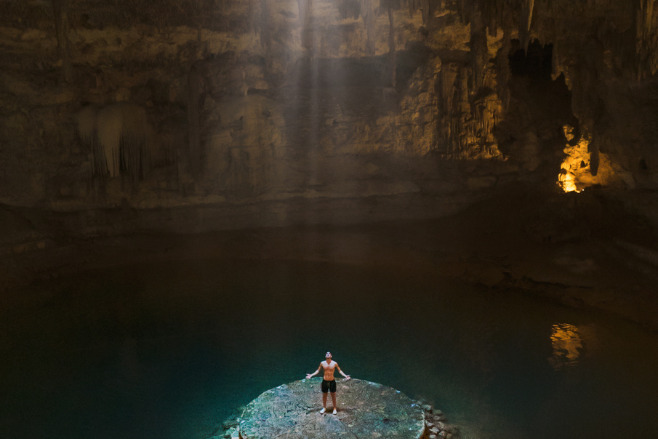 Man in a cenote, standing under a light, destination wedding pros and cons