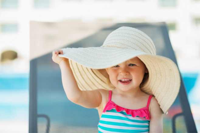 A baby with a beach hat on at the beach