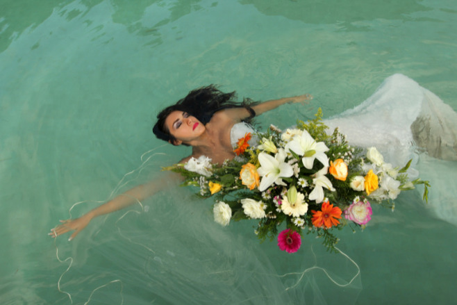 A bride in the pool doing trash the dress