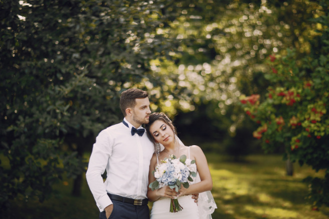 A happy couple in front of a forest after their destination wedding