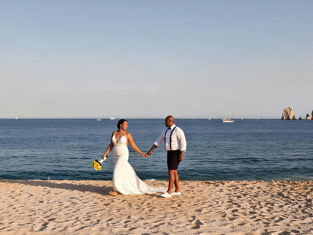 A couple in wedding attire holding hands on a sandy beach, capturing the beauty and charm of a dreamy destination wedding—though not without its destination wedding costs.