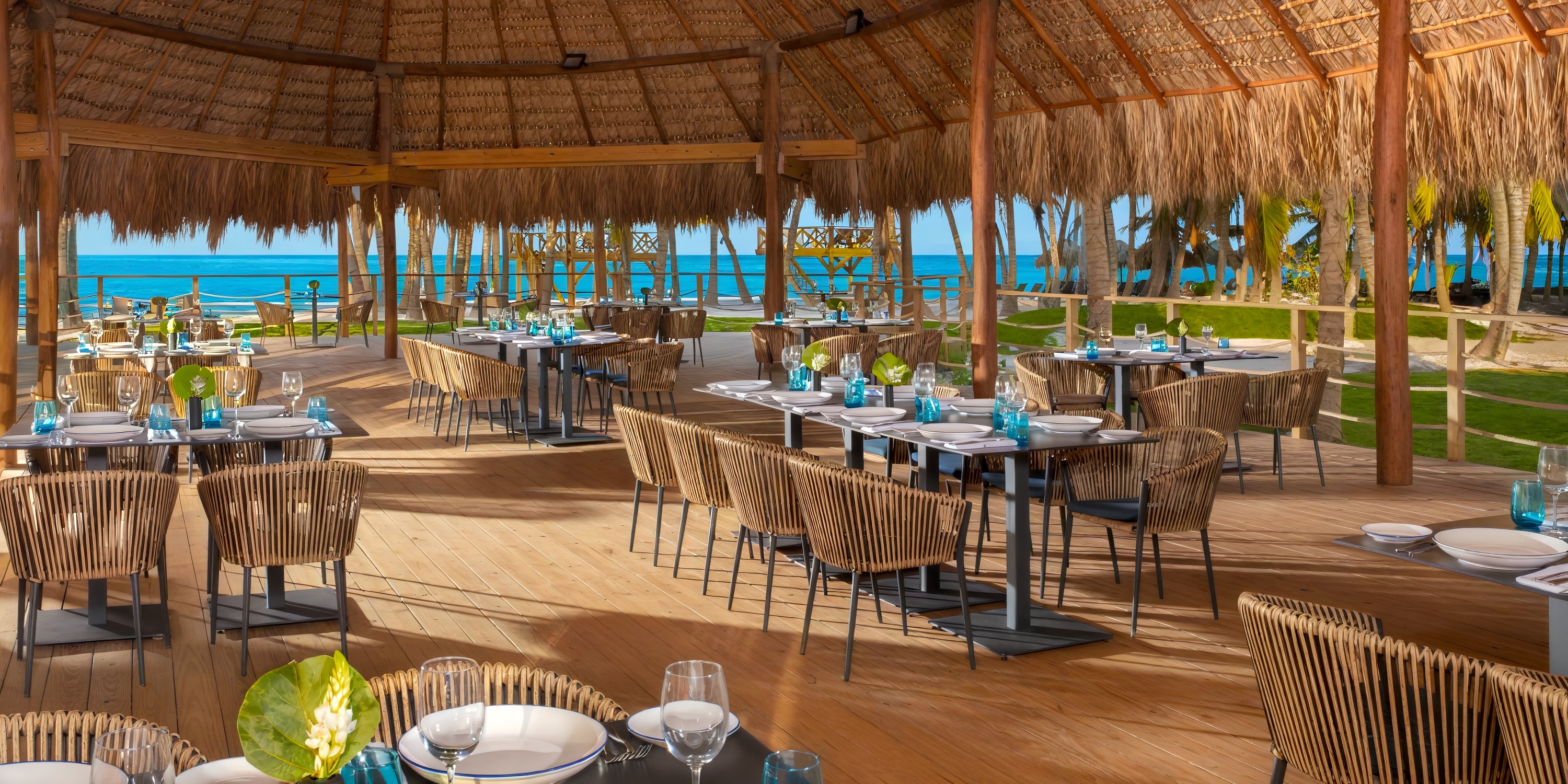 Dreams Flora: open-air restaurant with thatched roof, set tables, ocean view—ideal for a destination wedding.