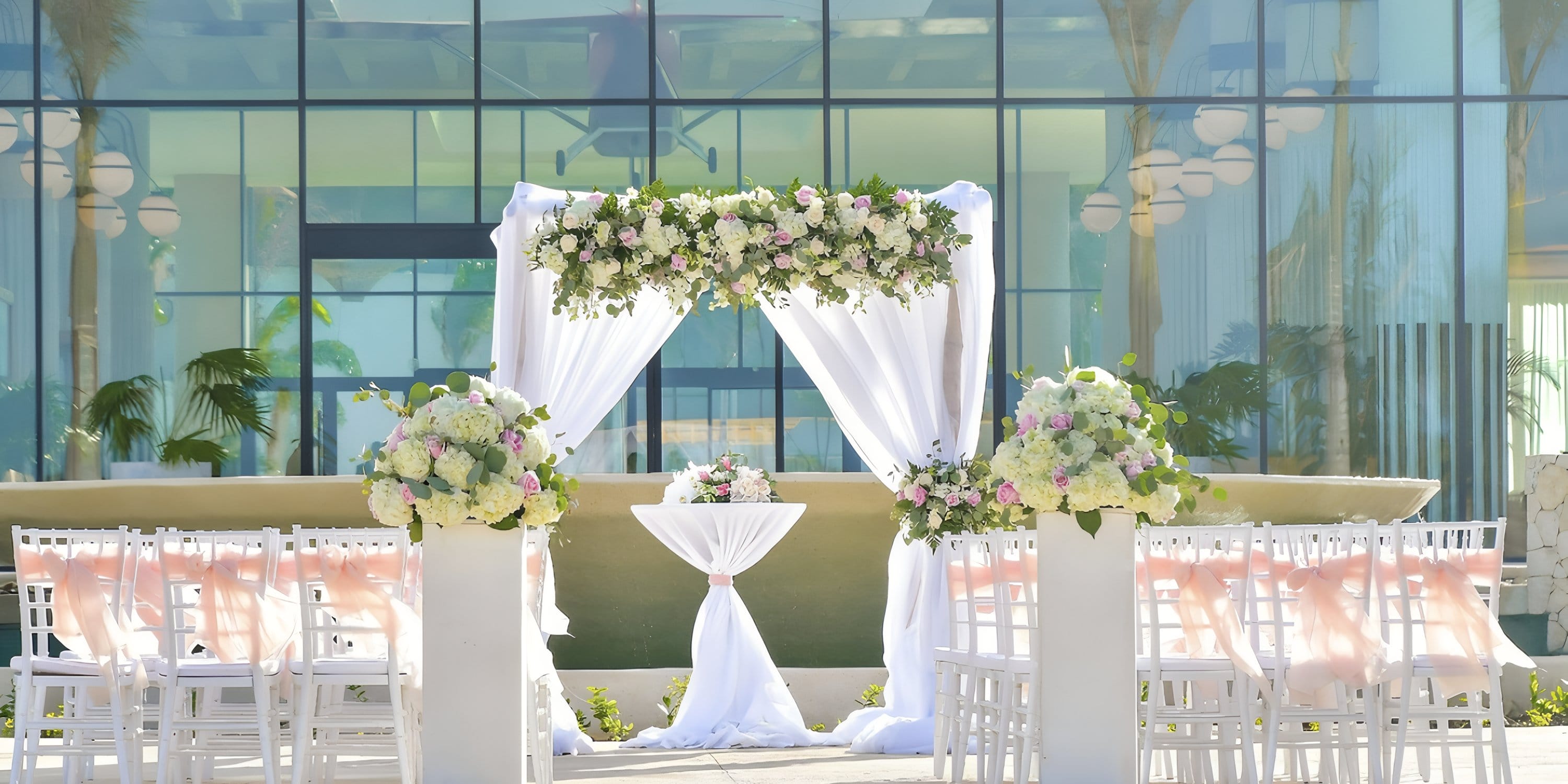 Destination wedding at Ocean Coral Spring: white chairs, floral decor, and a flower-adorned arch.