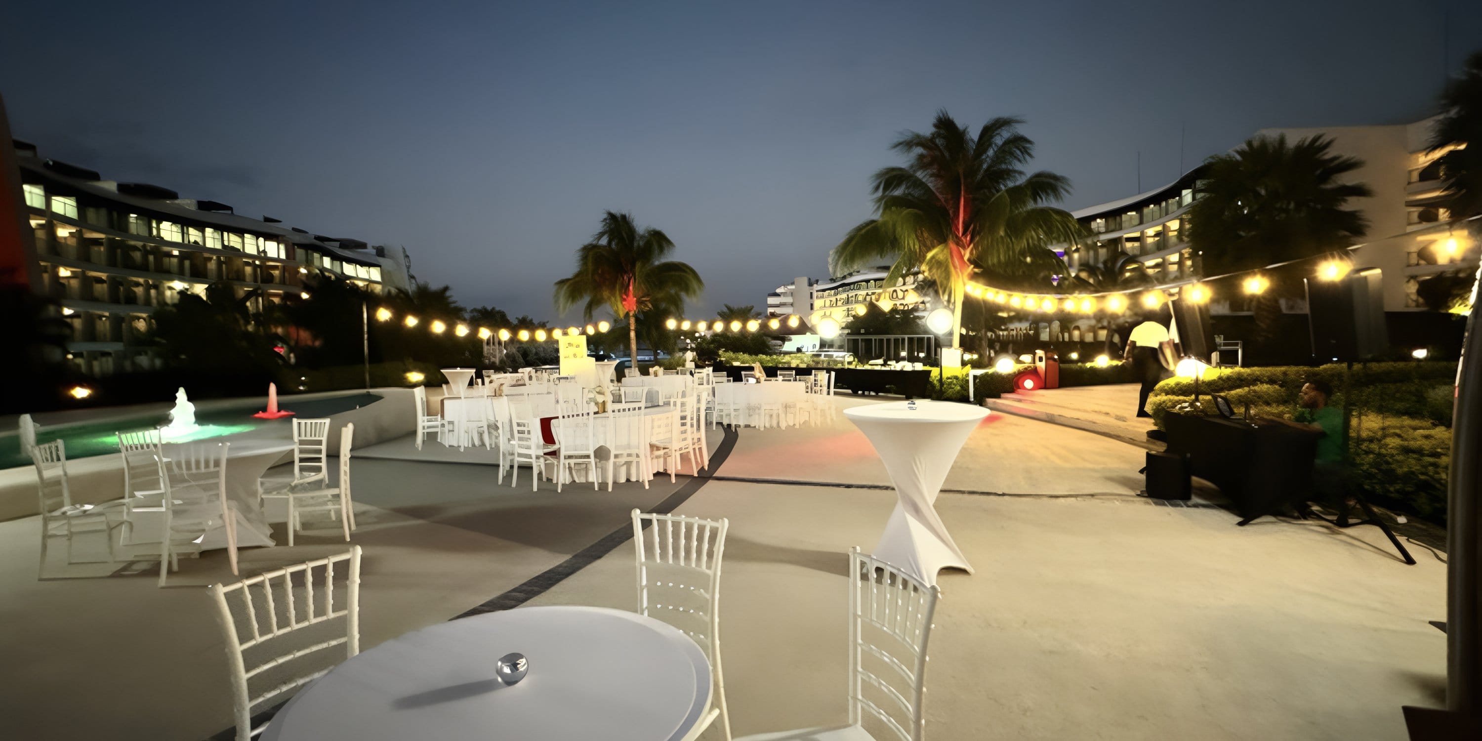 Ocean Coral Spring wedding: white chairs, round tables, string lights at dusk.