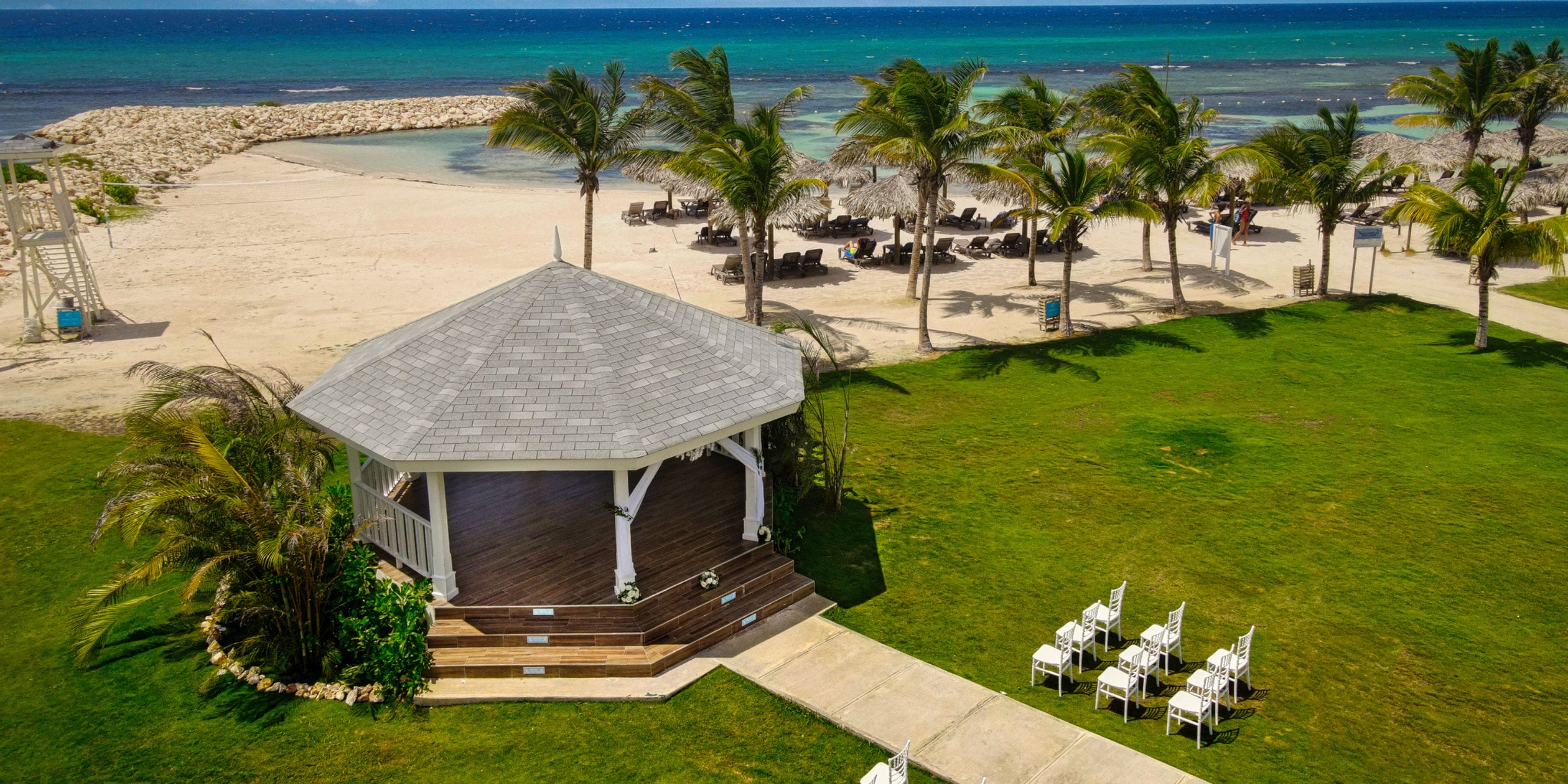 Ocean Coral Spring: white gazebo & chairs on lawn, ideal for a destination wedding by the ocean.