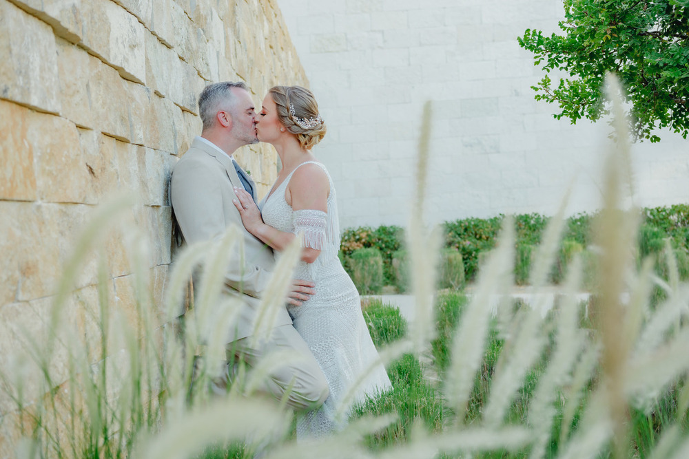 Destination wedding couple kissing against stone wall