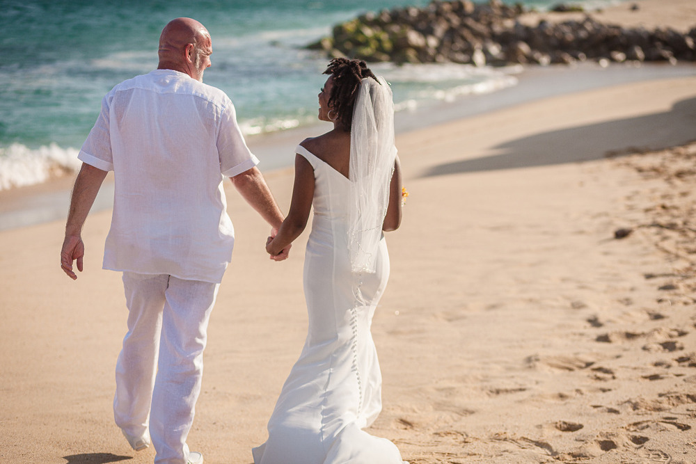 Couple, hand in hand, walking down the beach after their destination wedding