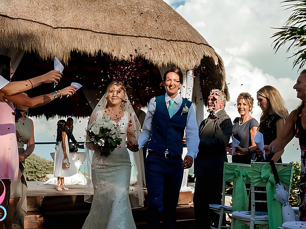 A bride and groom walk down the aisle at a The Knot wedding celebration, surrounded by flying confetti in a joyful wedding moment.