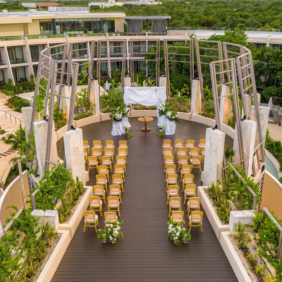 A destination wedding ceremony setup outdoors, with rows of chairs arranged toward a beautifully decorated altar.