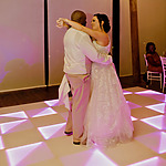 A bride and groom share a dance on a light-up dance floor at their destination wedding reception, looking into each other's eyes.