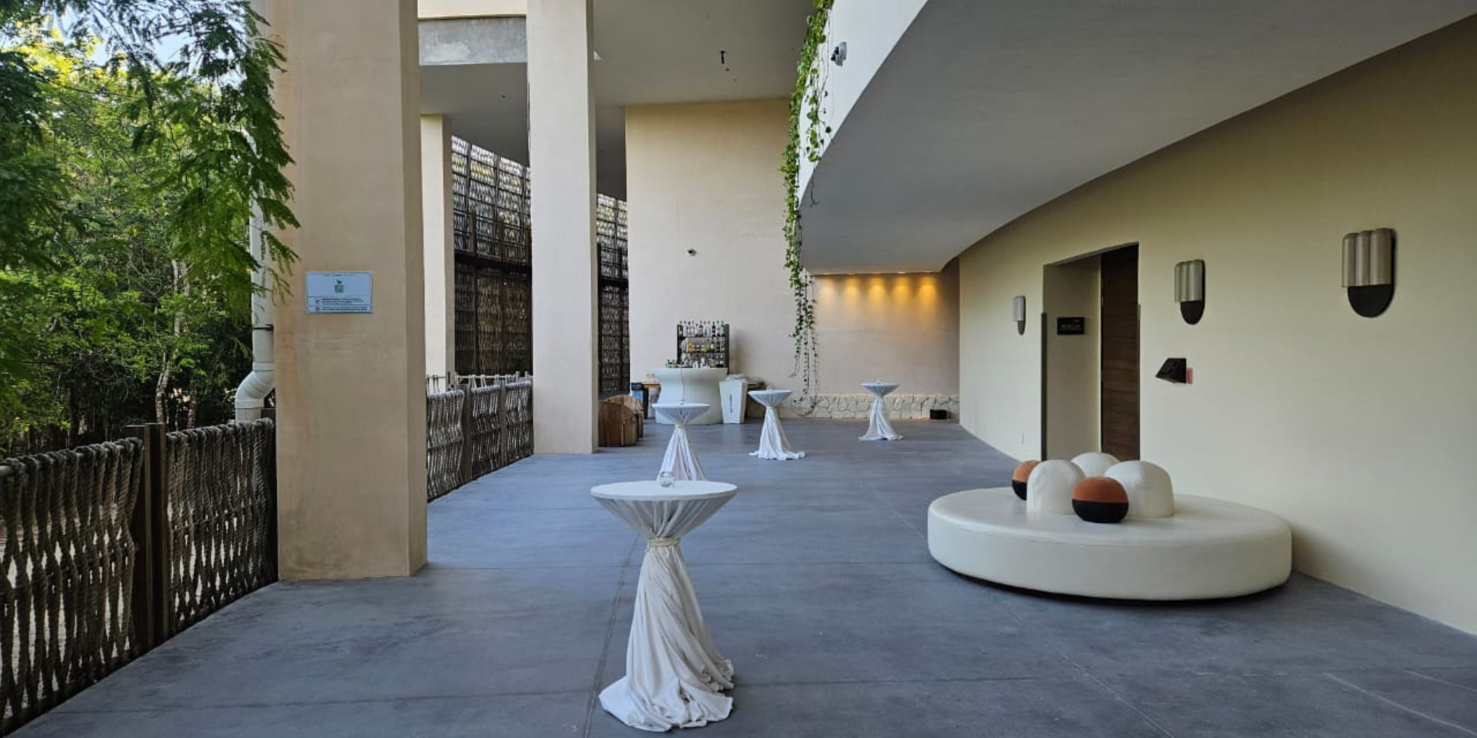 Secrets Tulum patio, perfect for a destination wedding, offers cocktail tables, sofa, lights, and greenery.