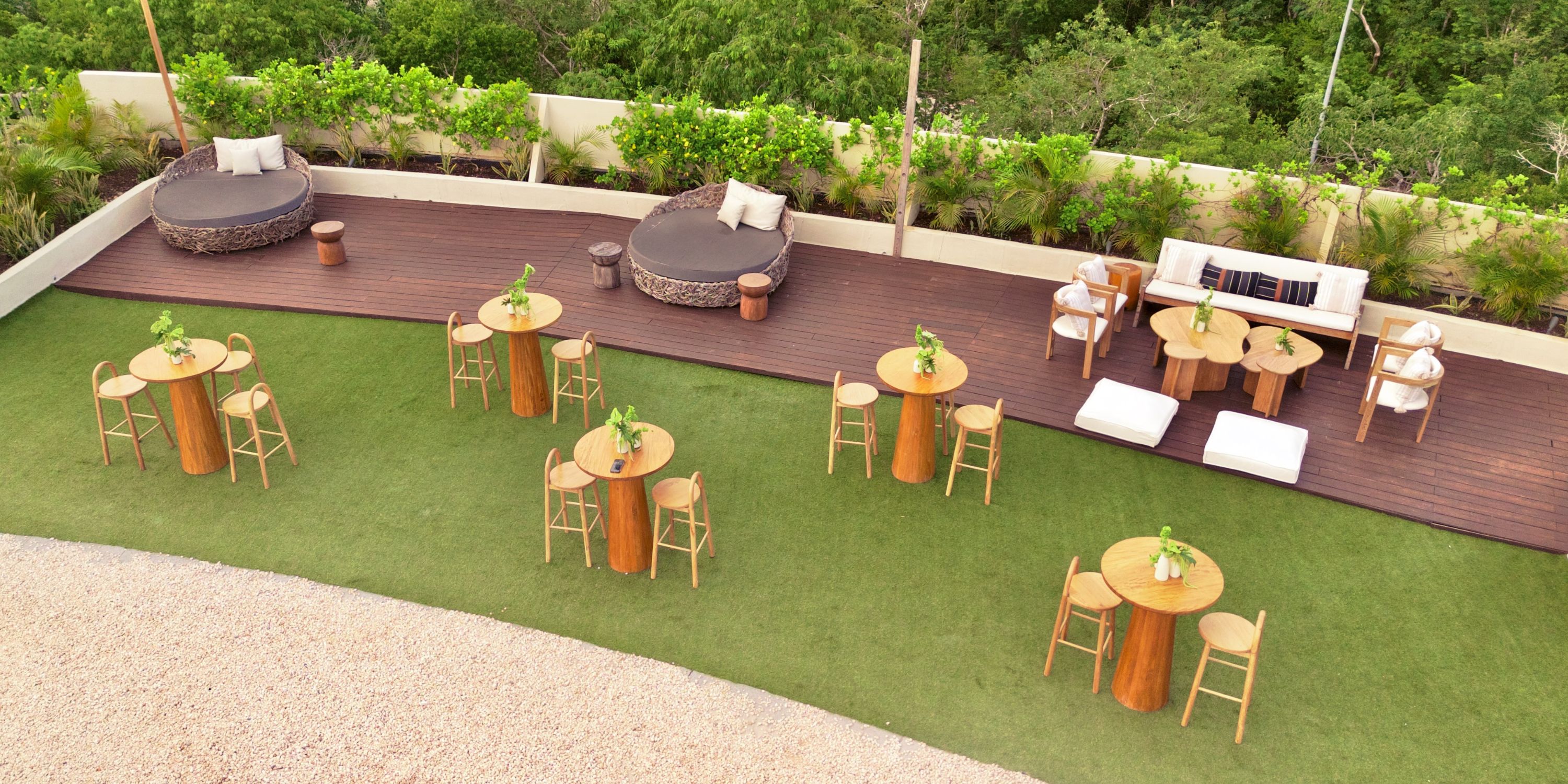 Secrets Tulum&rsquo;s outdoor area, ideal for a destination wedding, has round tables, lounge beds, and greenery.