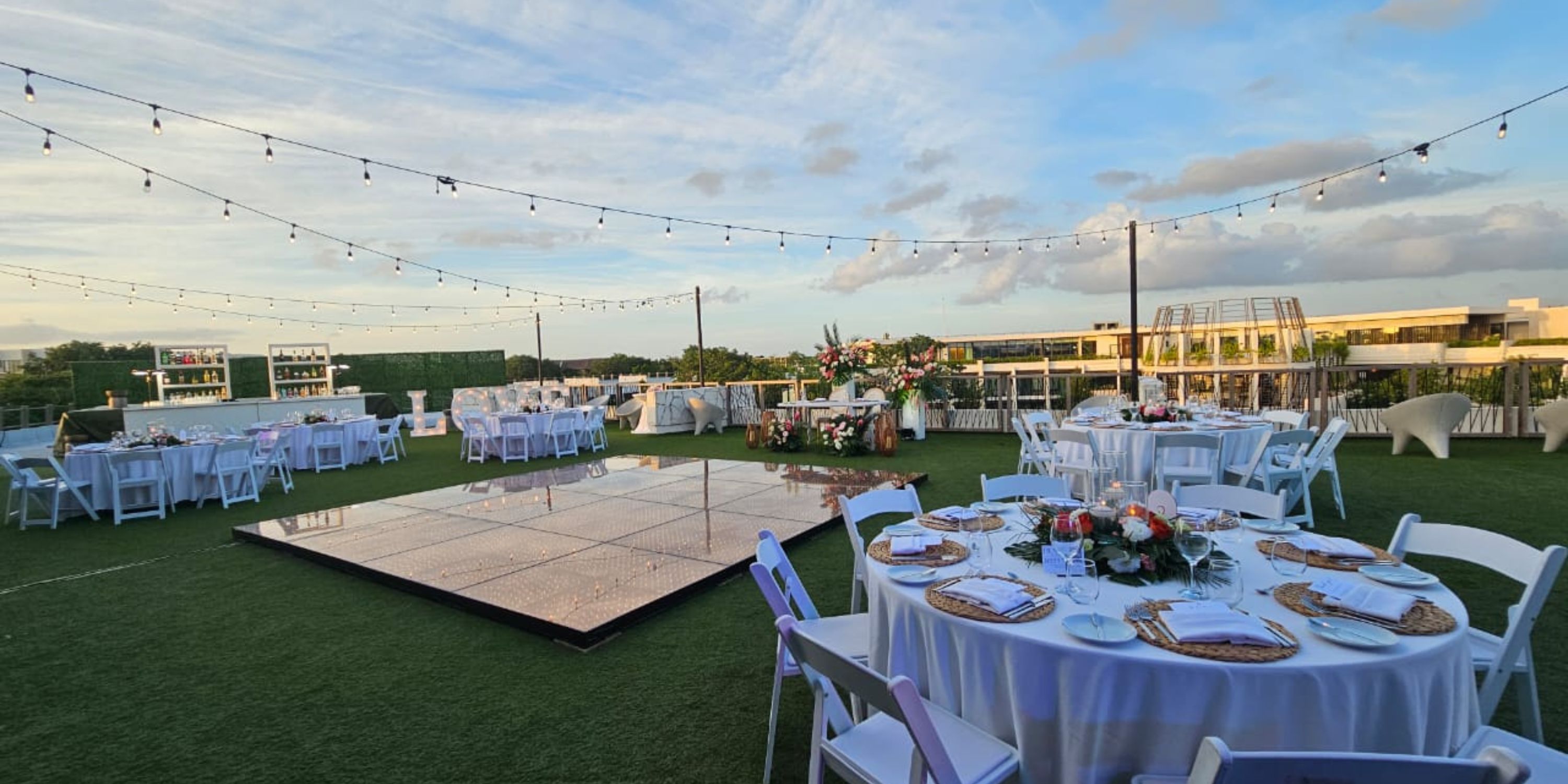 Destination wedding setup at Secrets Tulum with round tables, floral centerpieces, and string lights.