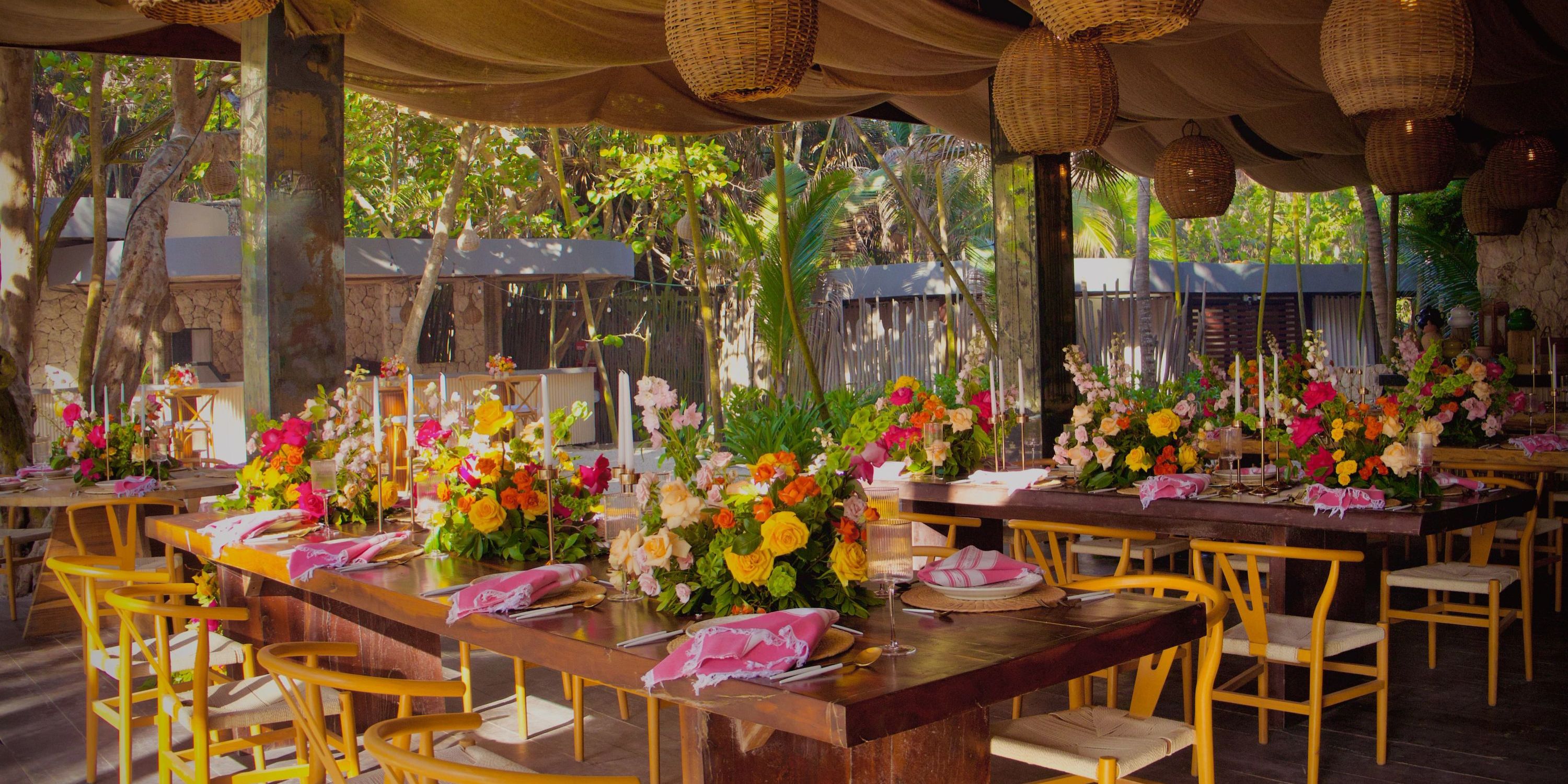 Celebrate a destination wedding outdoors at Secrets Tulum with wooden tables, yellow chairs, and floral decor.