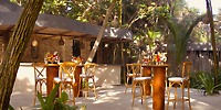 Secrets Tulum&rsquo;s outdoor bar has tall tables, wooden chairs, and floral decor&mdash;ideal for a destination wedding.
