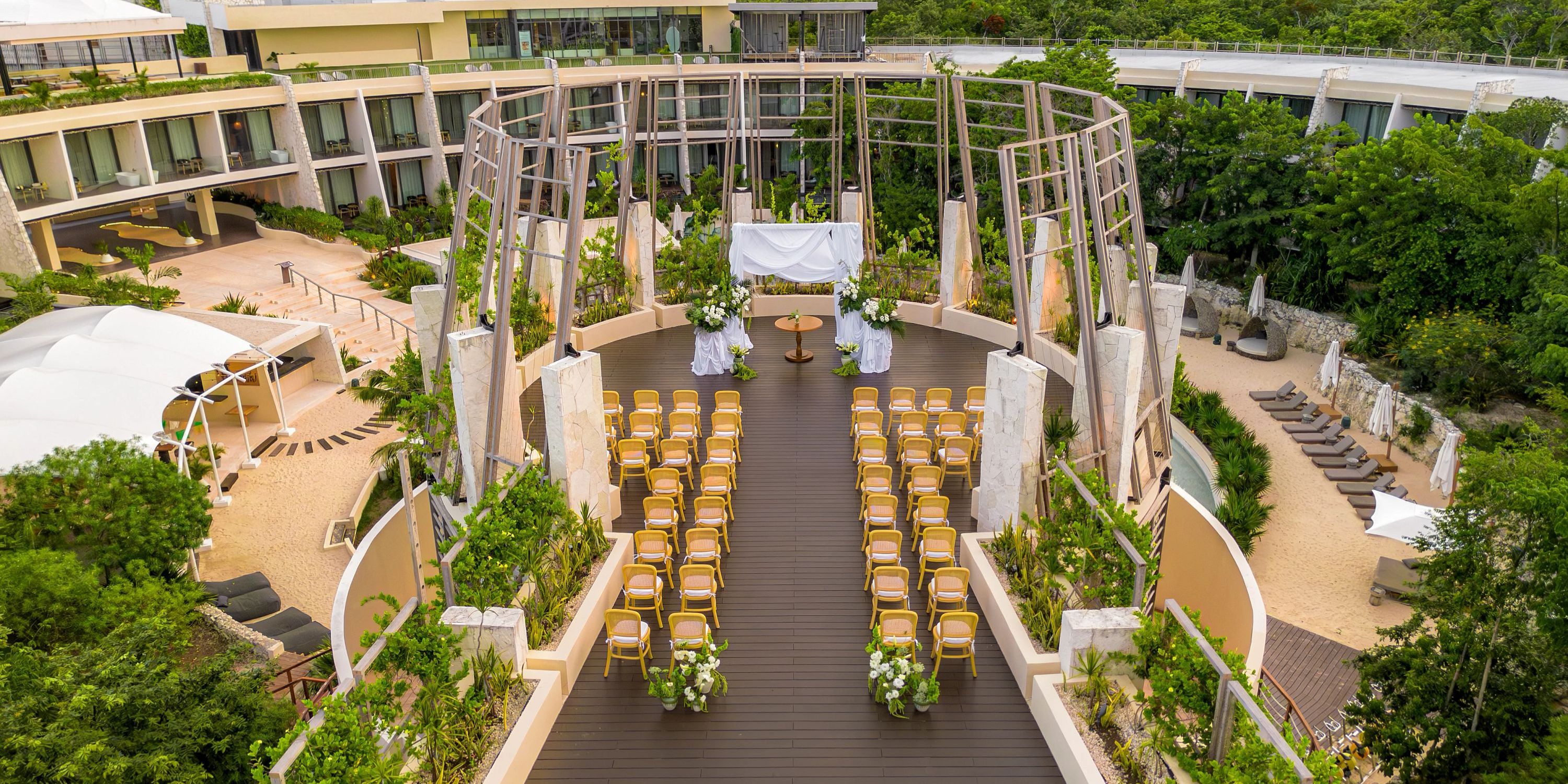 Destination wedding ceremony at Secrets Tulum with rows of chairs and floral d&eacute;cor on a wooden deck.