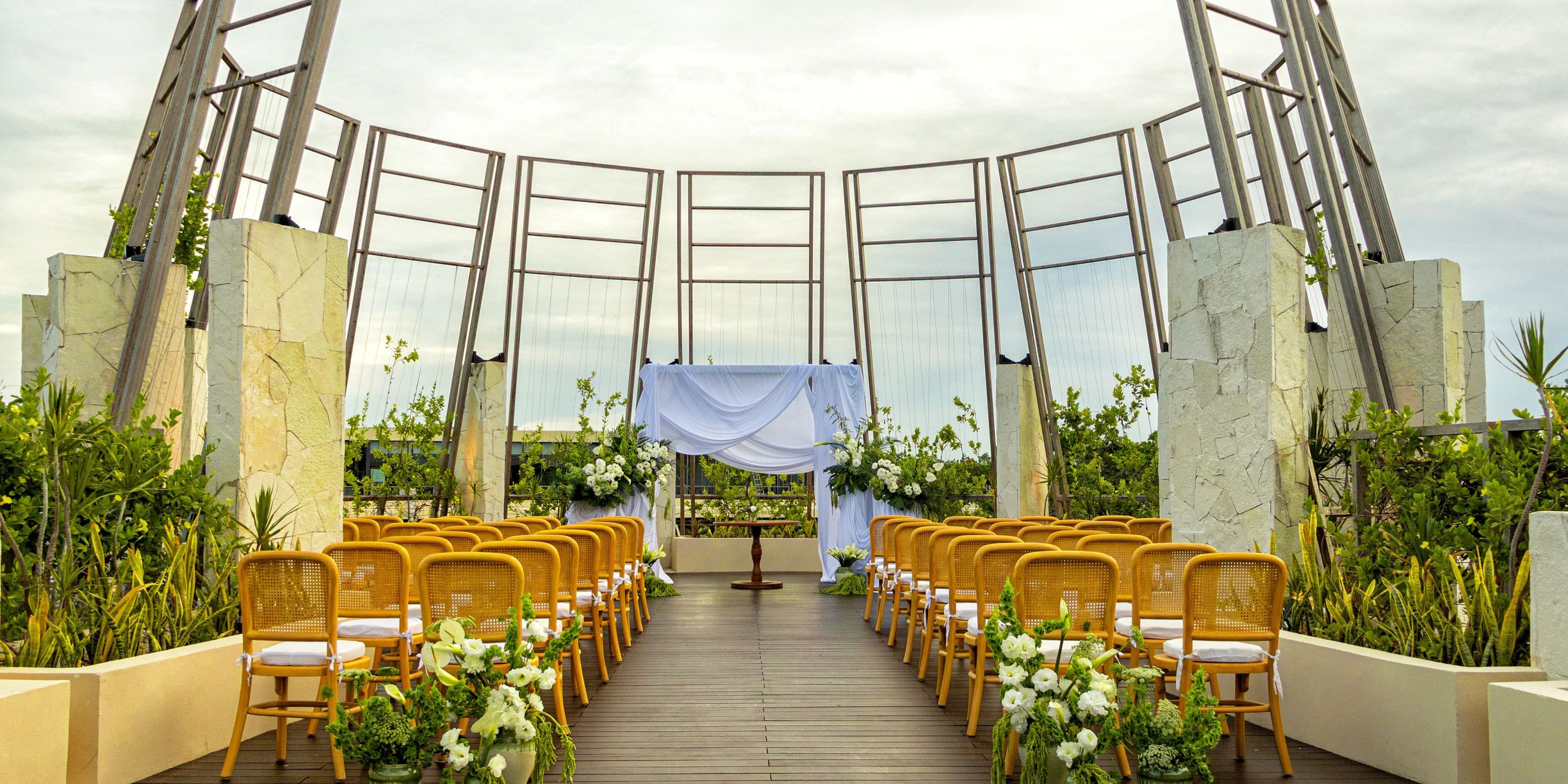 Destination wedding at Secrets Tulum featuring rows of chairs, floral d&eacute;cor, and a beautifully set altar.