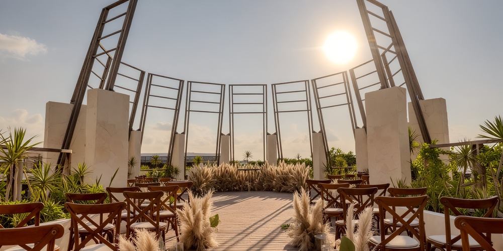 Secrets Tulum offers an enchanting outdoor setting, perfect for a destination wedding, featuring elegant seating, lush plants, and sunlit architecture.