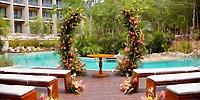 Destination wedding at Secrets Tulum by the pool, featuring floral arches and rows of white benches.